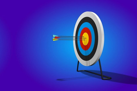 A archery target with three arrows in the bullseye