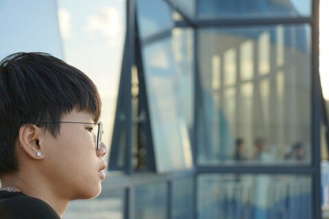 Asian American looking toward a glass building façade