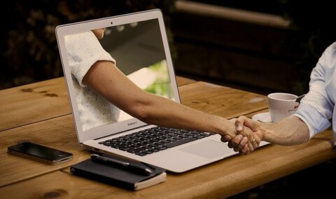 Image of a handshake with one hand coming out of a laptop screen