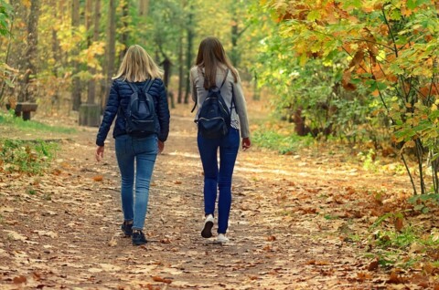 Two young women walking through an autumn forest