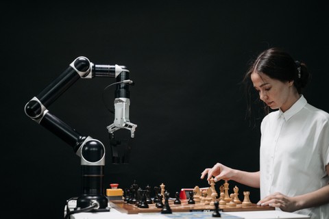 A young woman plays chess with an AI